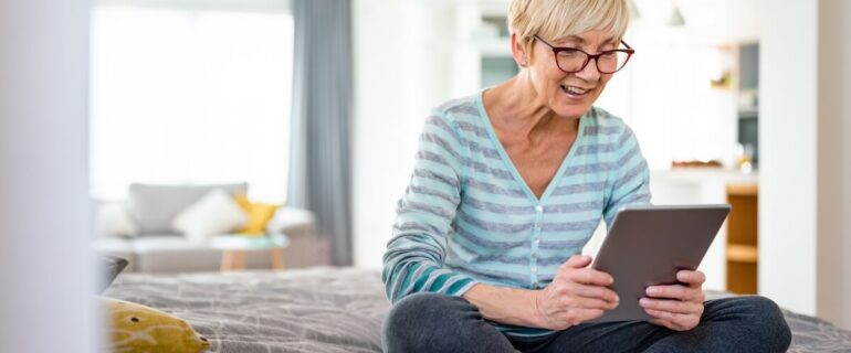 Mature woman reading latest mortgage rates on bed in home